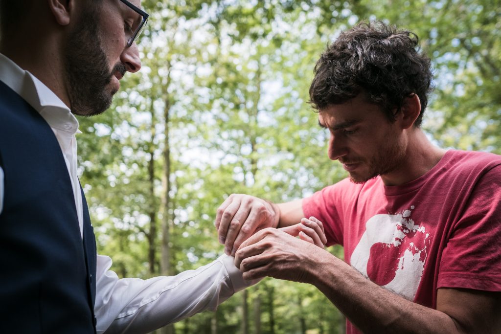 photgraphe mariage étangs de taysse le témoin aide le marié avec ses boutons de manchettes
